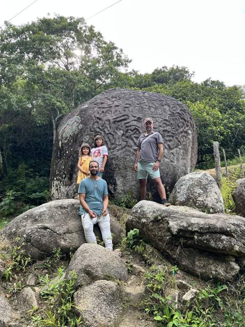 Personas junto a la gran roca de la Piedra de Donama, entre la vegetación de la Sierra